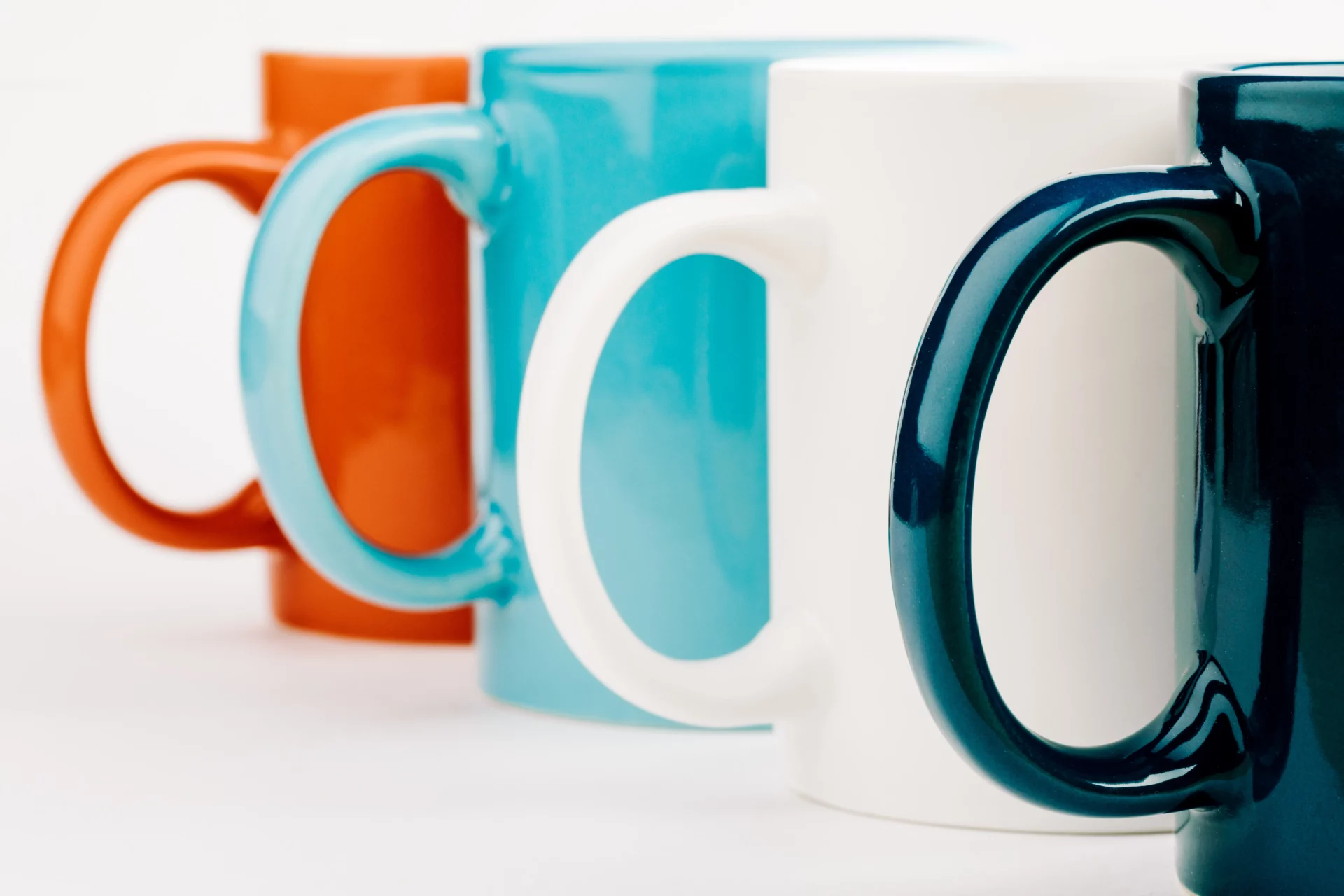 Une image contenant une rangée de quatre mugs de couleur