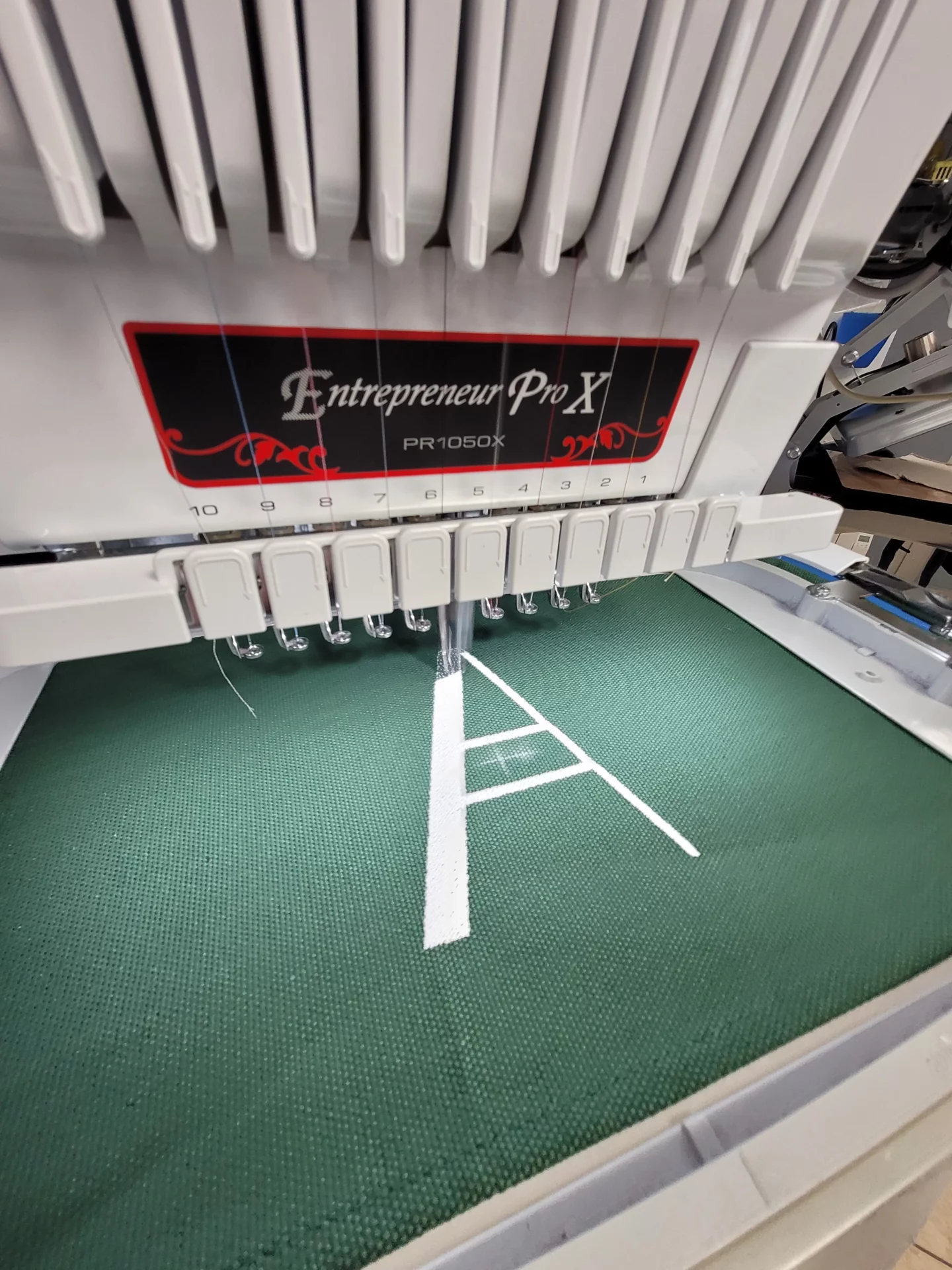 atelier-brod-art-creations-soissons-aisne-marquage-textile-broderie-chaise-cineaste-vert-personnalis Machine à broder professionnelle réalisant un marquage textile sur tissu vert pour une chaise cinéaste – broderie personnalisée sur toile épaisse par Atelier Brod’Art Créations à Soissons