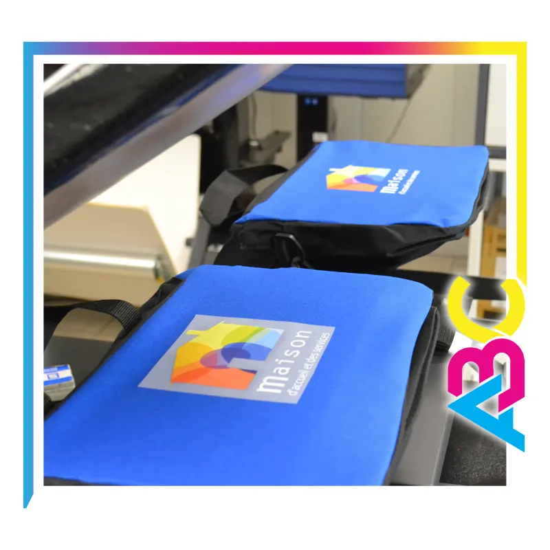 Impression DTF sur porte-document en cours à l’Atelier Brod’Art Créations – marquage en couleur sur presse thermique.